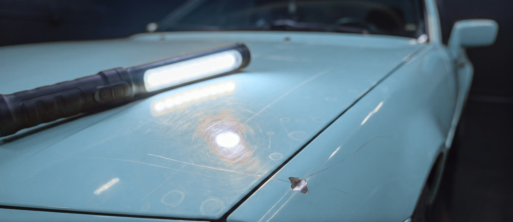 Close-up of paint under an inspection light showing swirl marks and scratches